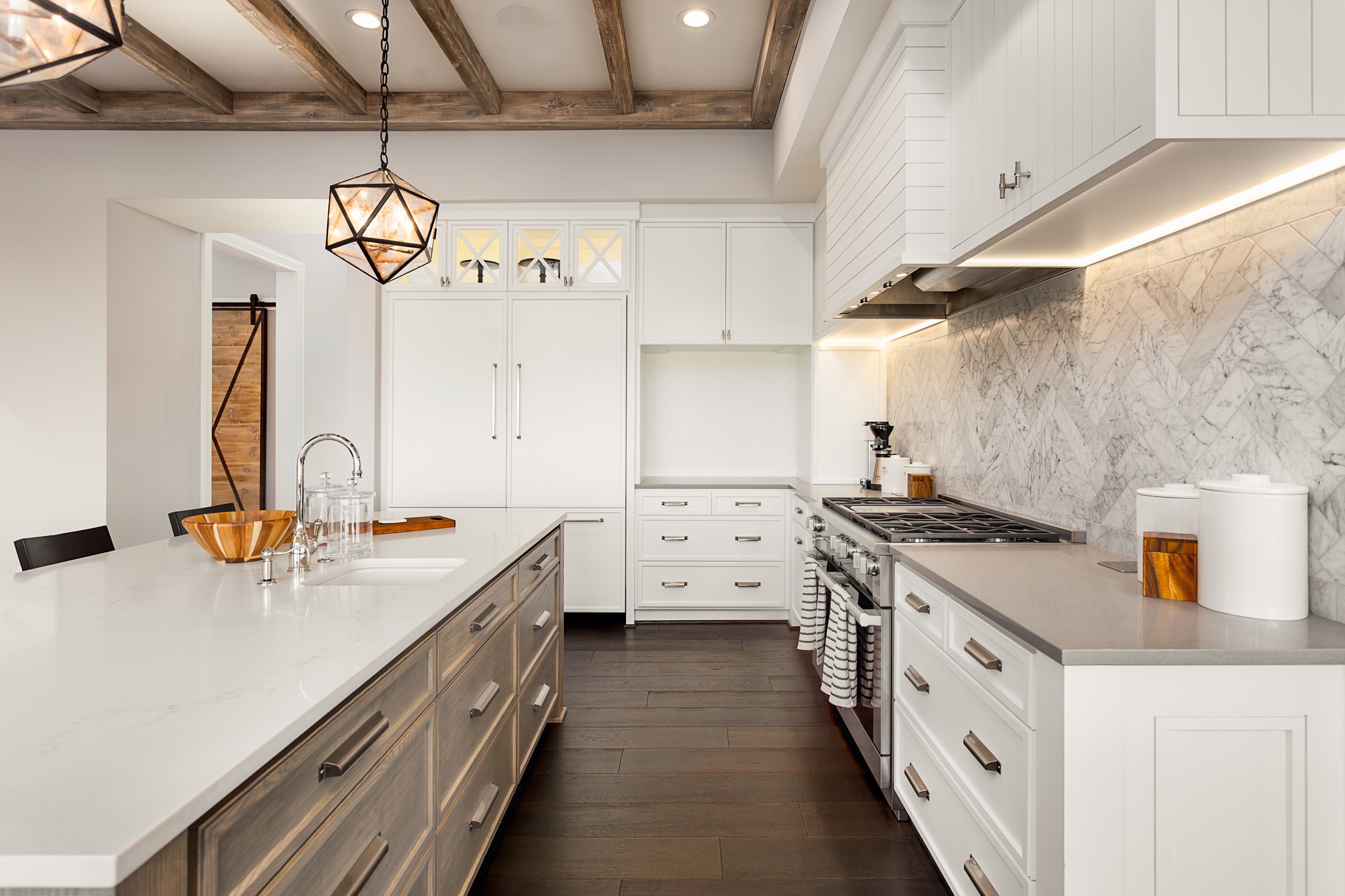 Marble tile backsplash seen between the upper and lower white cabinets of a clean, modern kitchen.