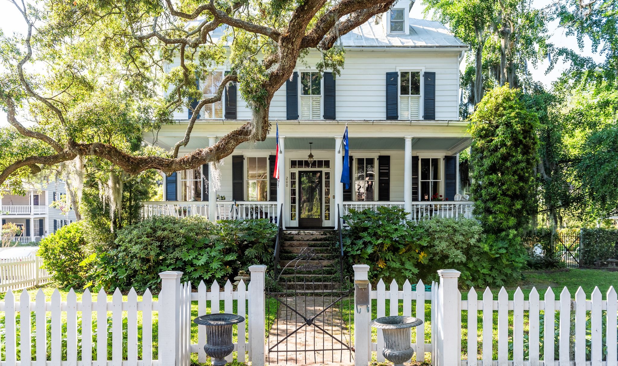 Historic white two-story home with columns and a picket fence.