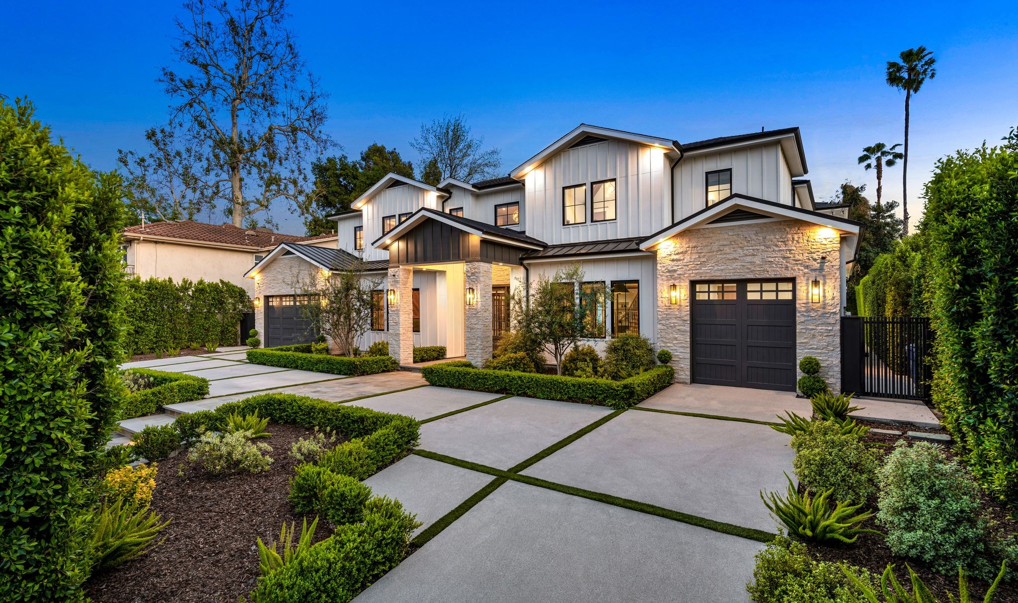 Beautiful modern home with elaborate driveway surrounded by a twilight glow in the sky.