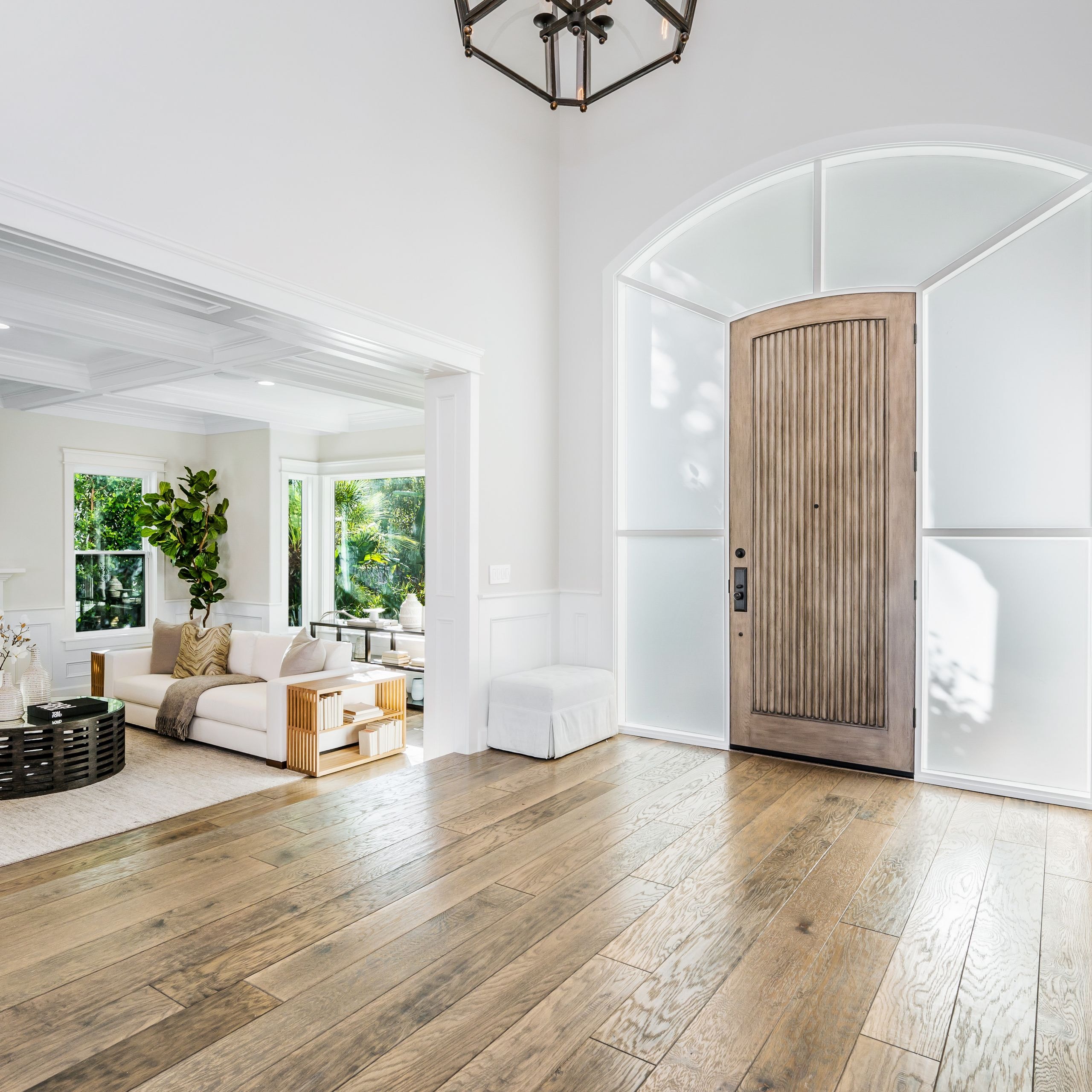 Elaborate frosted glass windows surround an ornate wooden front door inside a home.